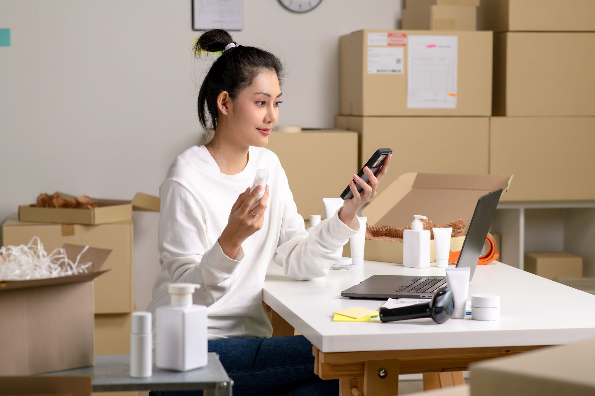 Asian e-commerce seller inspecting and sorting products for customers, in a warehouse setting for an online beauty shop.